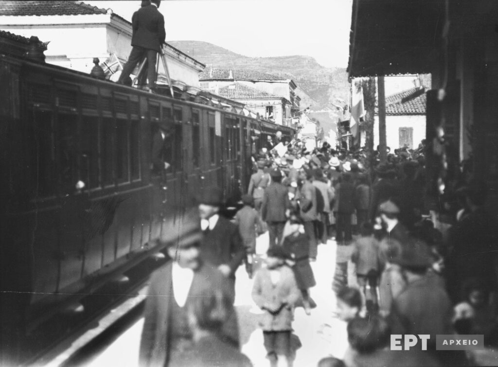 Άποψη της πόλης το 1924 με αμαξοστοιχία τρένου σε στάση, κατά τη διάρκεια του εορτασμού των 100 χρόνων από το θάνατο του Λ. Βύρωνα. Αρχείο Ε.Ρ.Τ. Α.Ε., Συλλογή Πέτρου Πουλίδη.